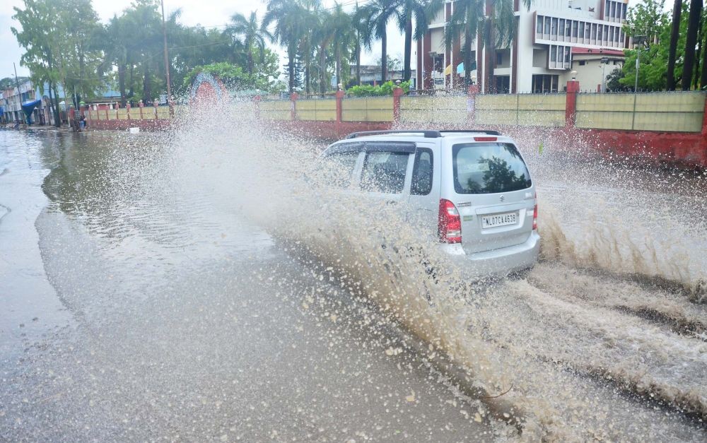 (Left) A vehicle passes through a water logged street after a heavy rain storm in Dimapur on April 23. (Photo by Caisii Mao) (Right) An uprooted tree brings down an LT line near the Pranabanda Women's College on Sunday.